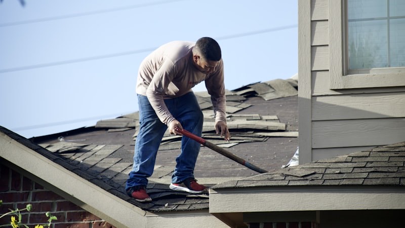 A roofer repairing shingles on a roof