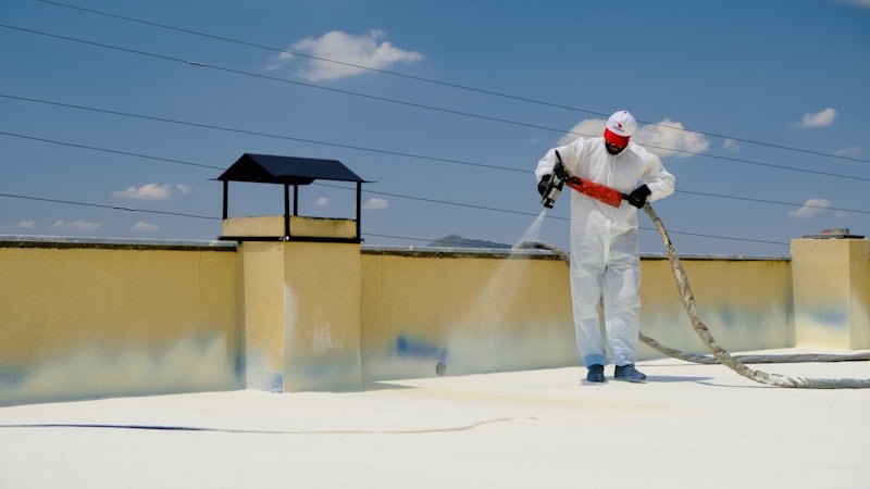 A roofer applying a waterproof coating to a flat roof